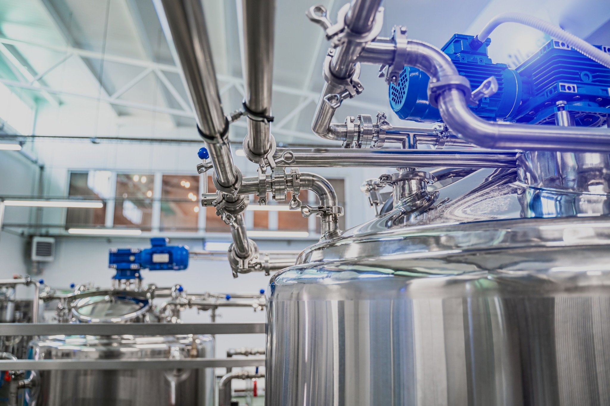 Industrial stainless steel processing equipment with pipes and motors in a factory setting.