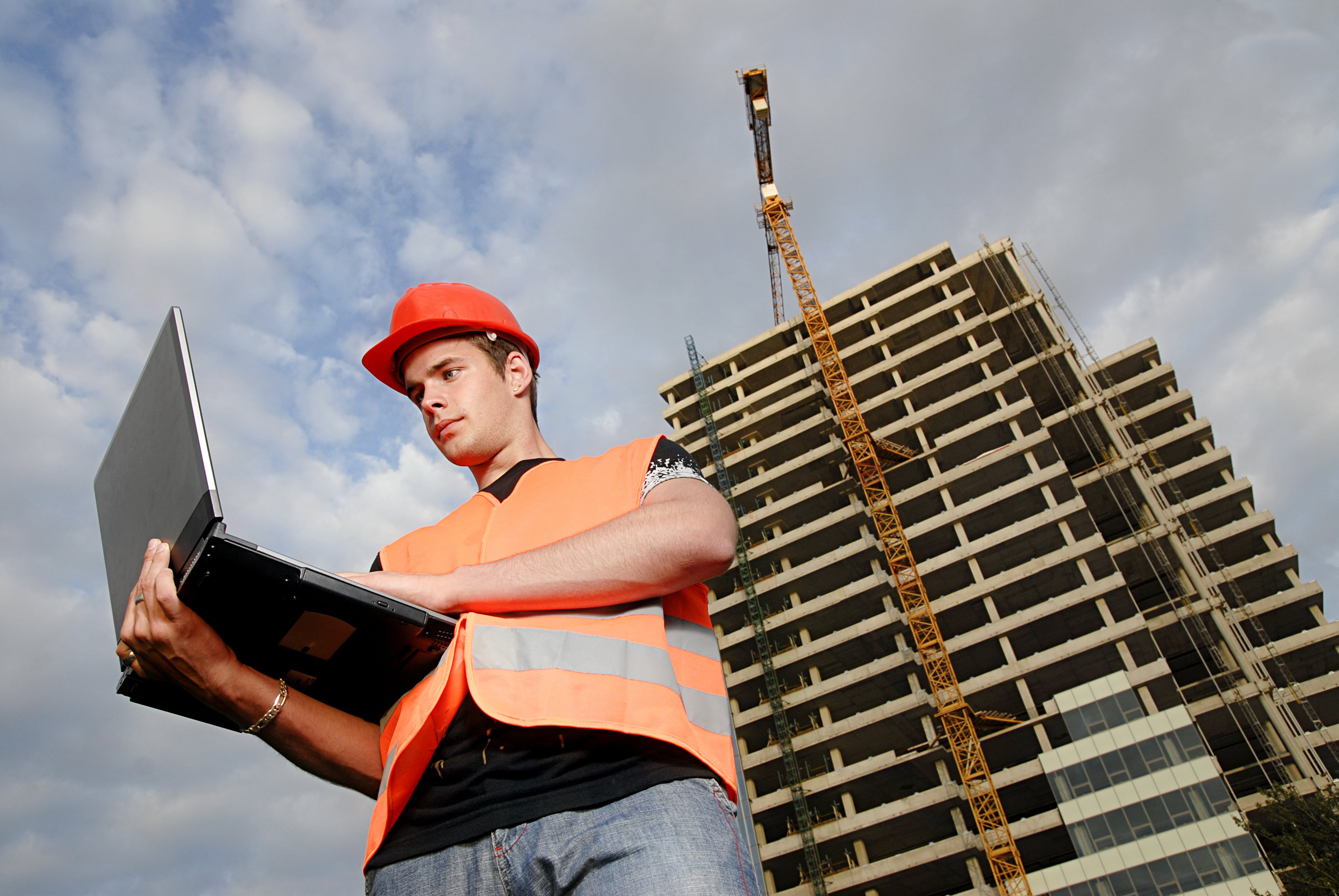 Construction Supervisor In Safety Helmet And Reflex Vest With Notebook In Front Of Construction Site Shutterstock 3972973 Edit Min